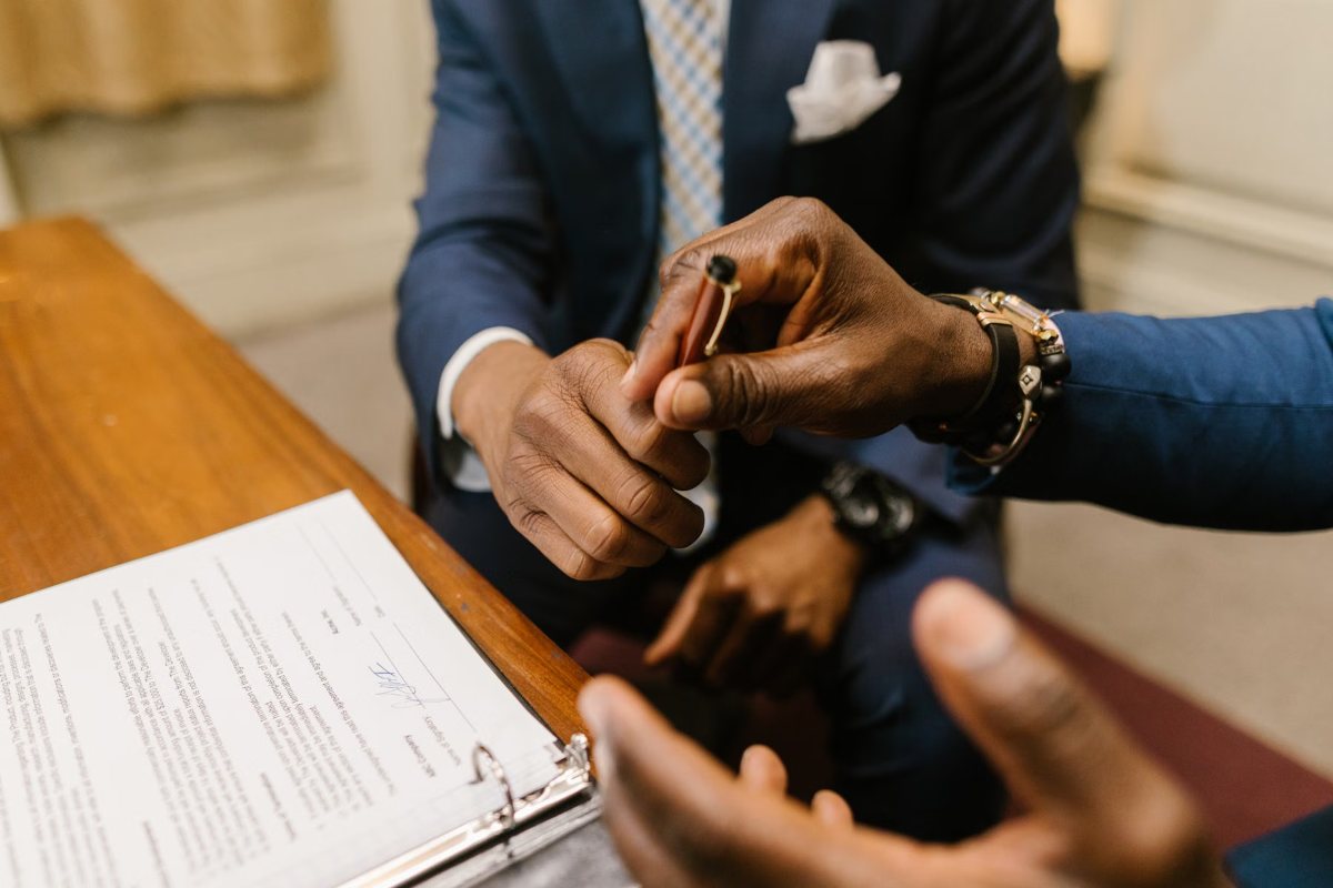 Two business professionals shaking hands over a signed contract