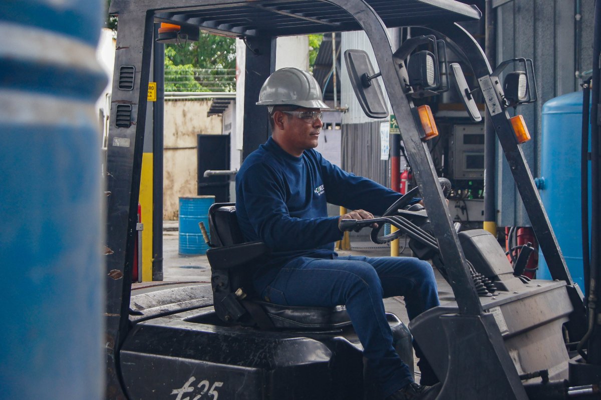 Worker in protective gear operating a forklift inside a warehouse